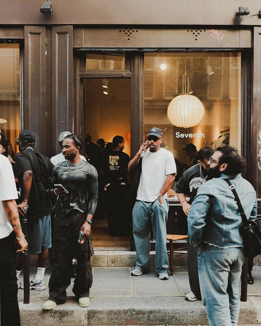 People standing outside a store with a prominent 'Seventh' sign on the window.