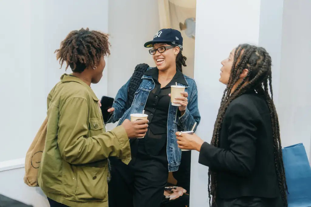 Three people socializing and holding drinks in a casual setting.