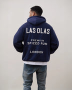 Person wearing a navy hoodie with 'LAS OLAS' branding on the back against a plain background