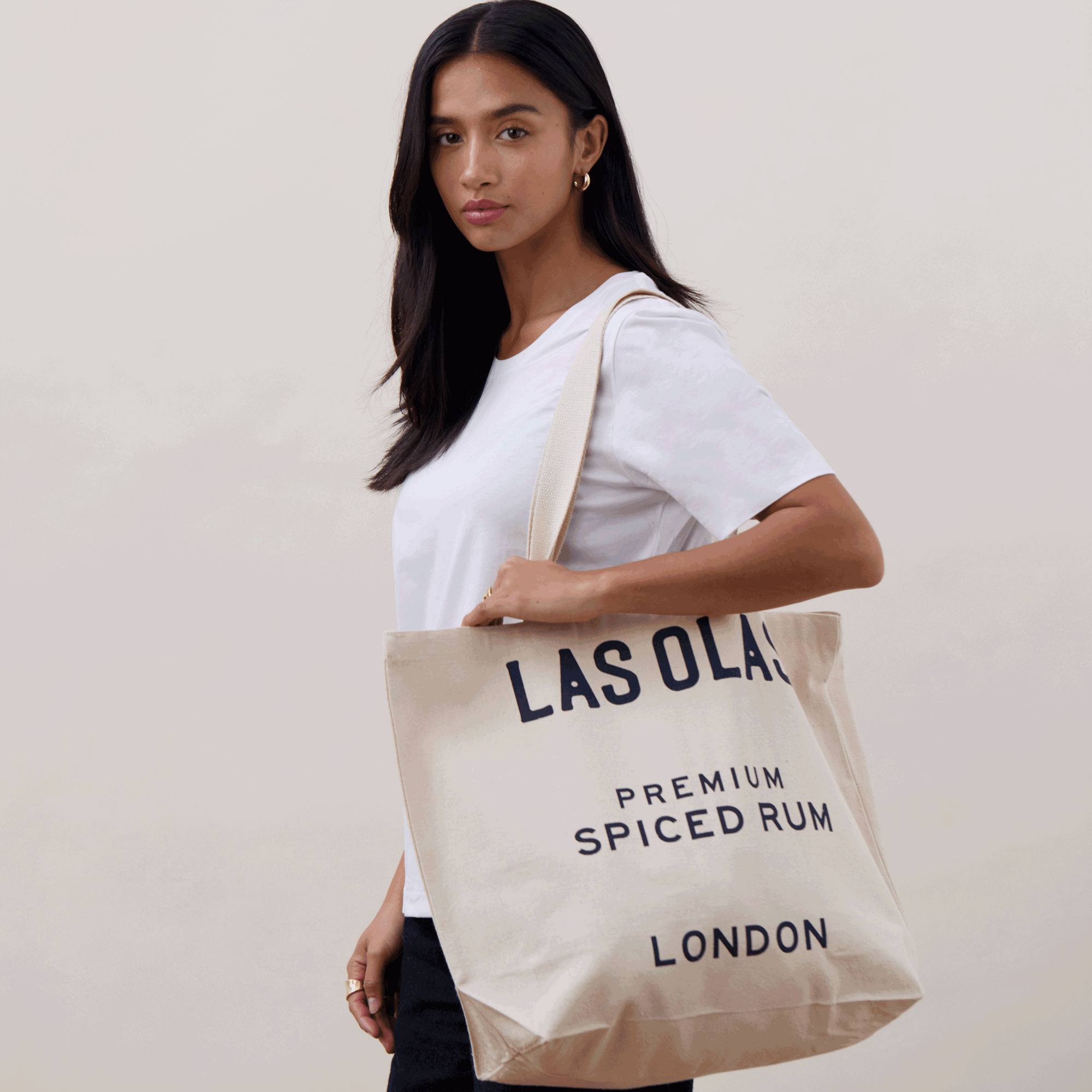 Woman holding a beige tote bag with text, against a plain background