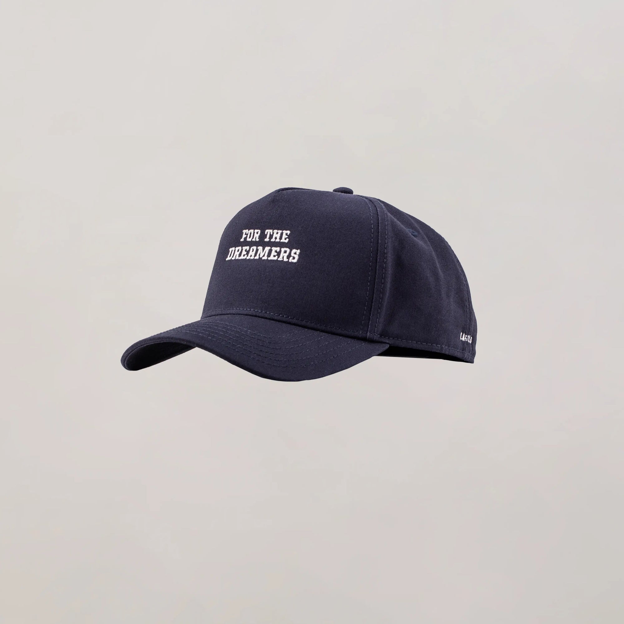 Navy blue cap with 'FOR THE DREAMERS' text on a light gray background