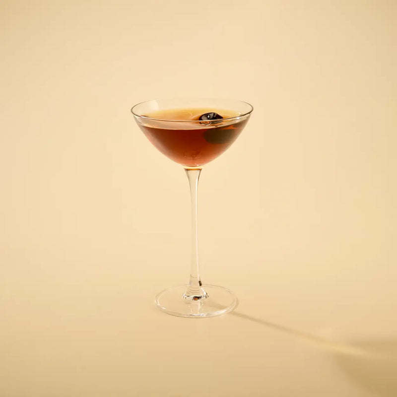 Cocktail in a glass with a dark liquid on a beige background