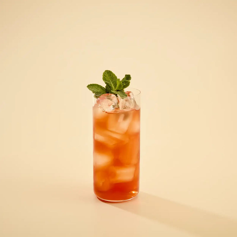 Cocktail with ice and mint leaves in a glass on a beige background