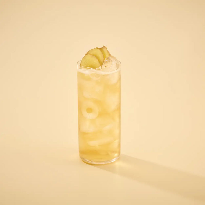 Glass of yellow cocktail with a slice of lemon on a beige background