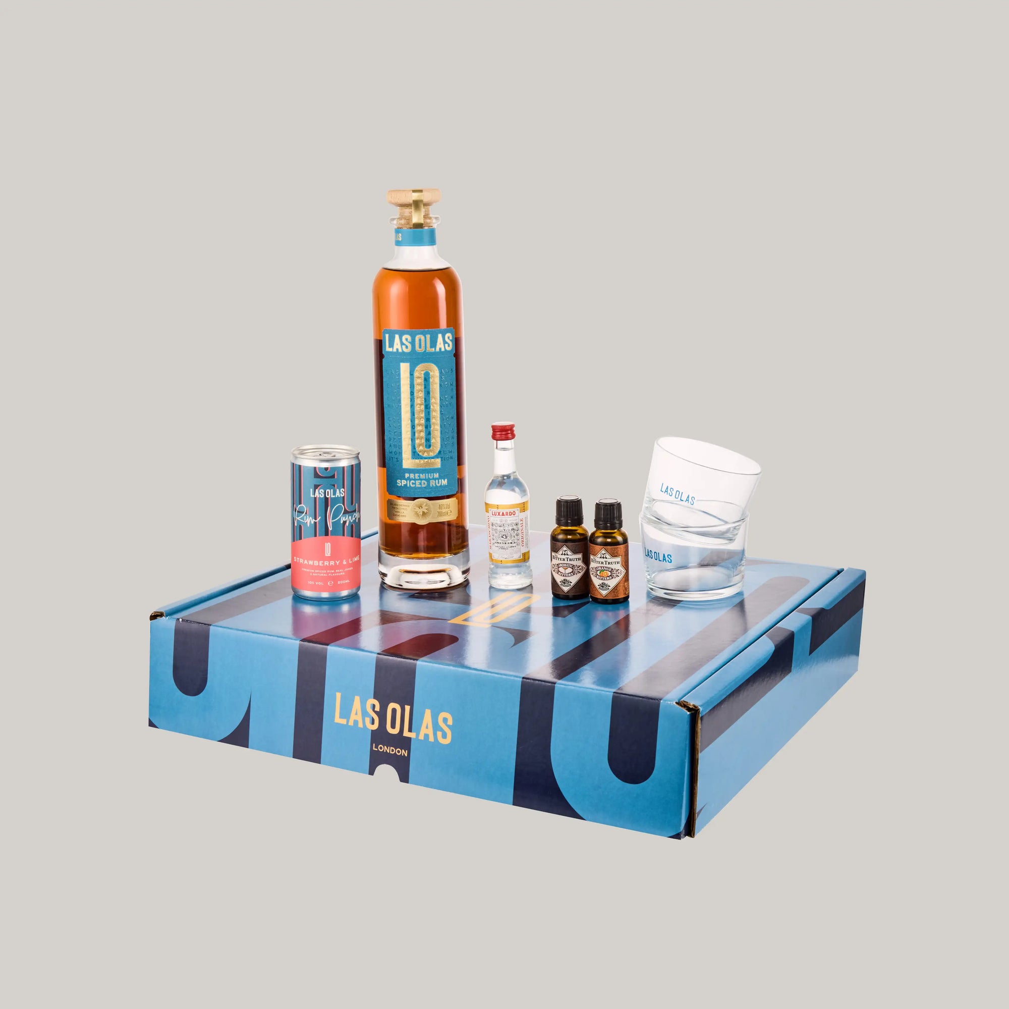 Las Olas bottles, rum punch can and accessories on a Las Olas branded box against a grey background