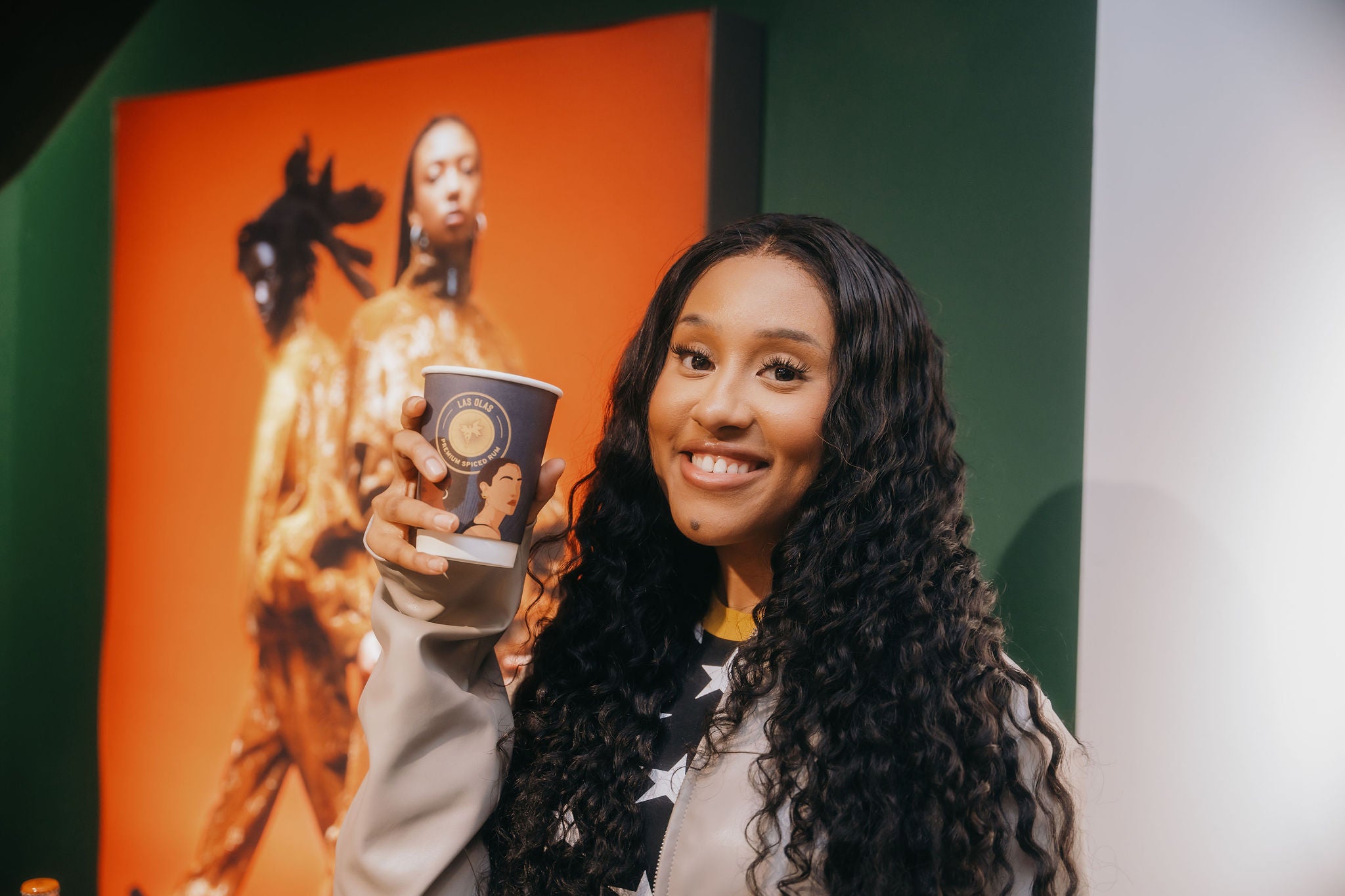 Woman holding a las olas cup with a colourful background
