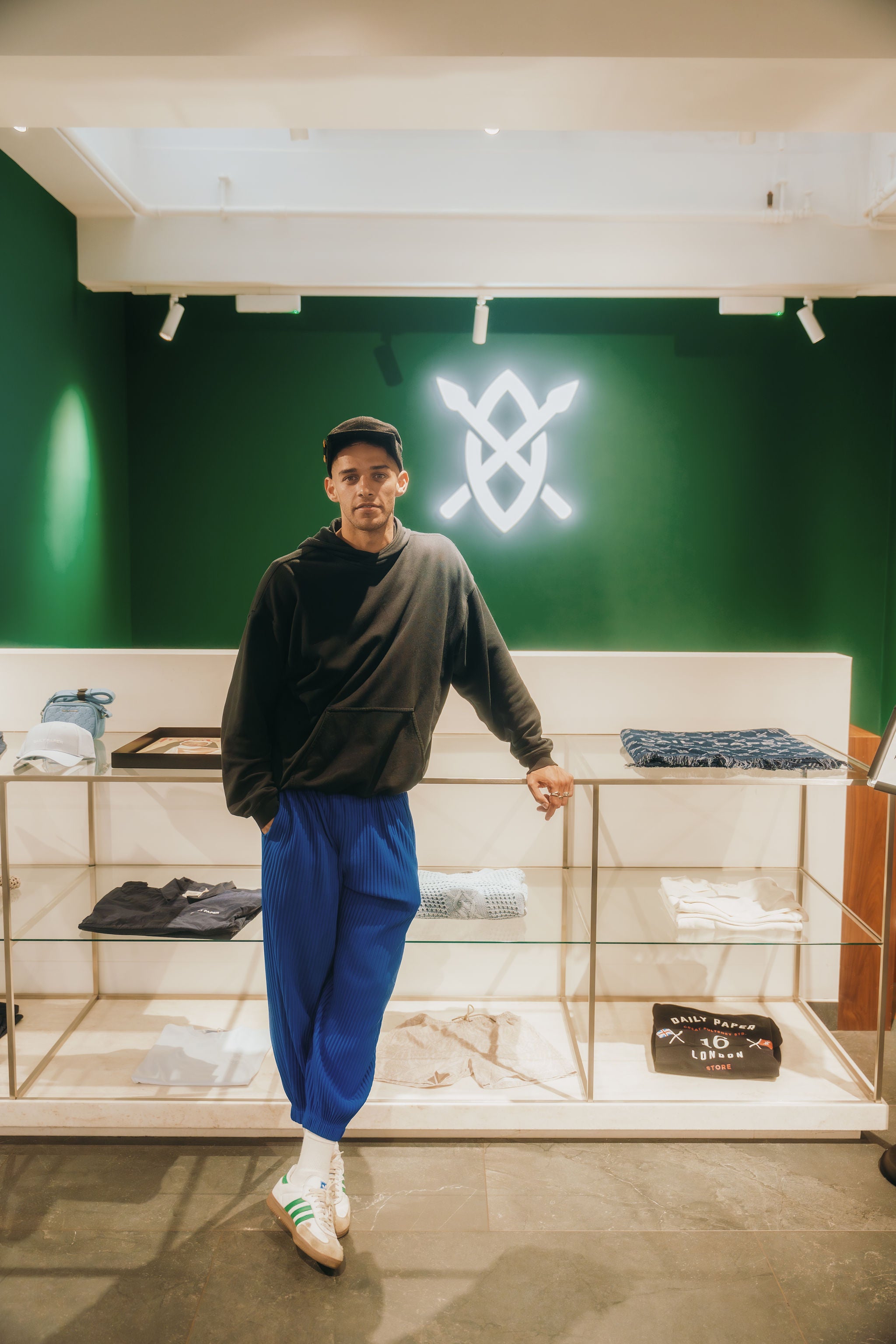 Person standing in a store with a green wall and neon sign.